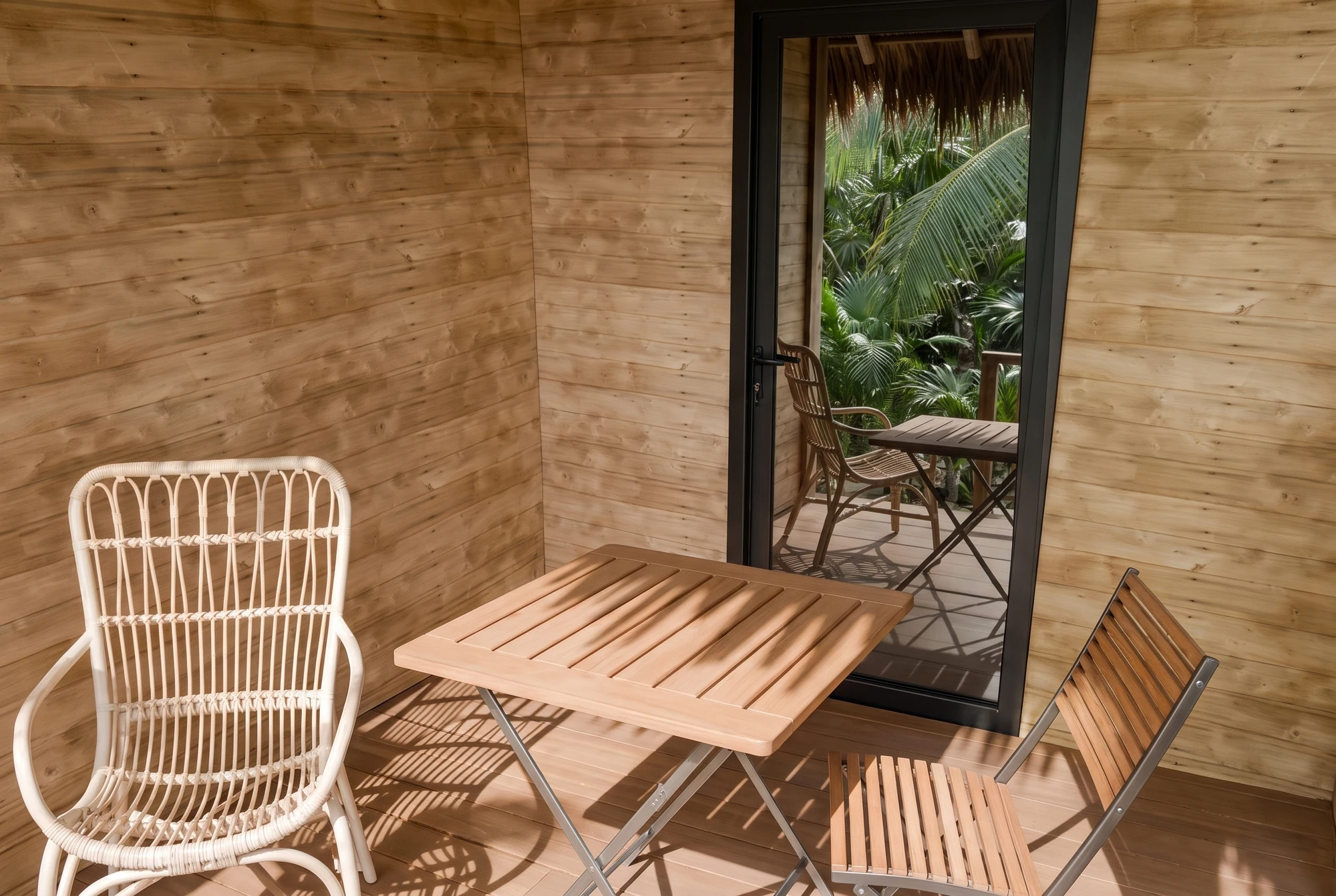 Timber dining table with woven and folding chairs beside the veranda doorway.